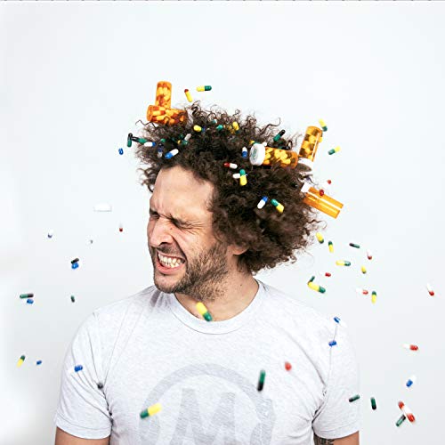 "Man with curly hair and white t-shirt, surrounded by falling confetti and capsules."