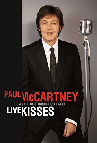 Paul McCartney in a suit, standing by a vintage microphone.