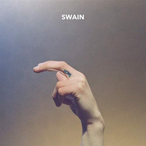 Hand with "HOWL" tattooed on a finger, against a blurred background.