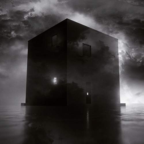 Dark, cubic structure surrounded by mist under a cloudy sky.