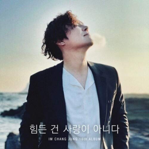 Man in black suit and white shirt stands outdoors with Korean text overlay.
