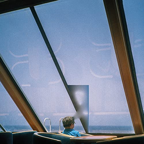 Person seen through a window with geometric wooden framing.