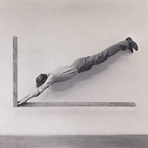 Black and white image of a man balancing on a corner.