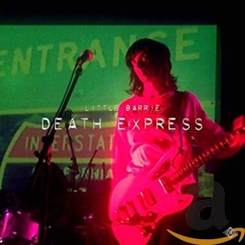 Musician playing pink electric guitar onstage with green and red backdrop.