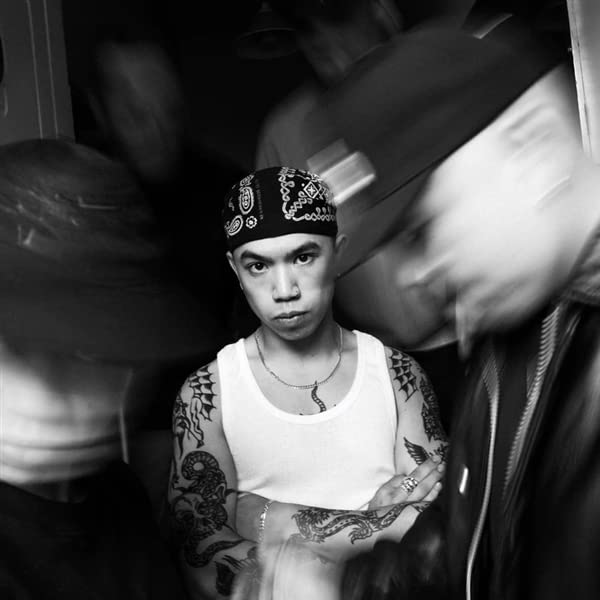 Black and white photo of a young man with tattoos and a bandana.