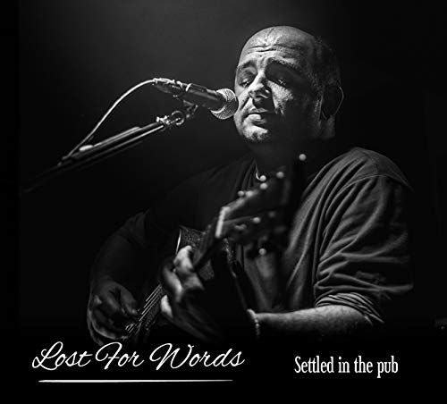Black and white portrait of a man singing into a microphone with guitar.