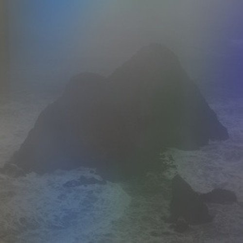 A dark, jagged rock formation shroudedC shrouded in thick blue and grey fog.