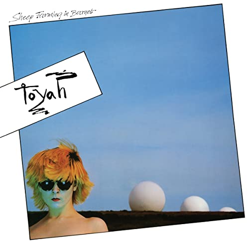 Toyah album cover with orange hair, sunglasses, and white spheres.