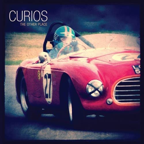 Red vintage race car with driver, album cover for "Curios.