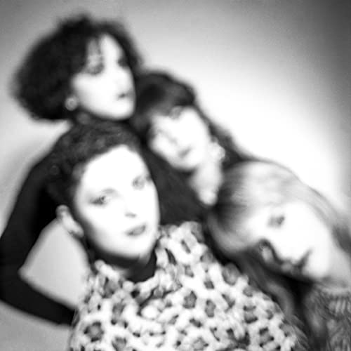 Black and white portrait of four women, slightly blurred, looking at camera.