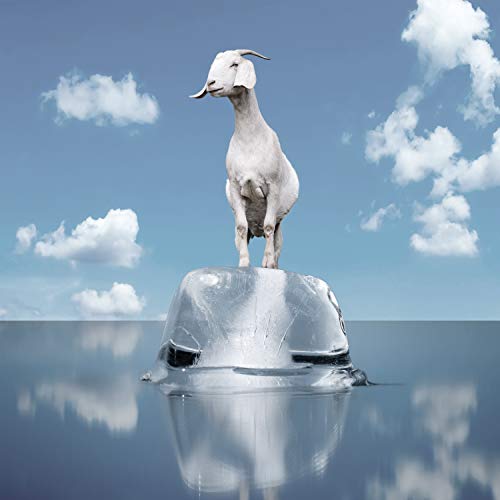 A white goat stands on an iceberg in calm blue water with fluffy clouds.
