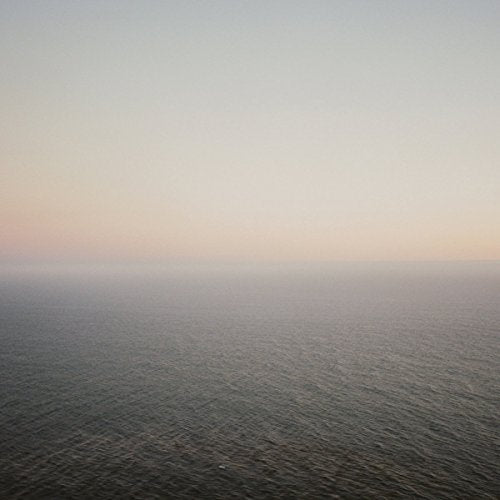 A calm, dark ocean meeting a pale, hazy sky at the horizon.