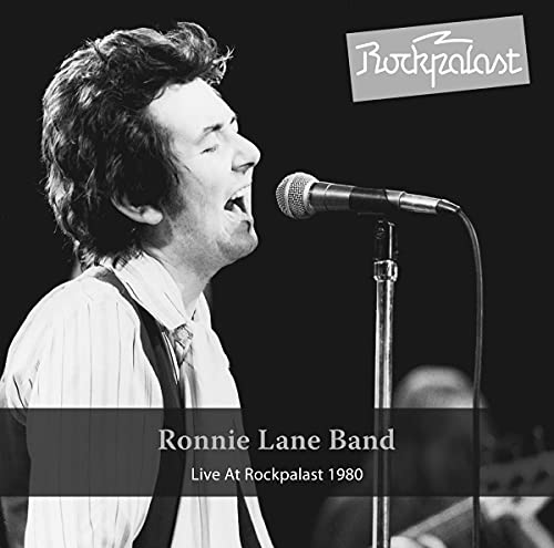 Black and white photo of Ronnie Lane singing into a microphone.