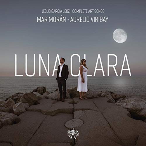 "Album cover with man and woman standing on rocks by the water under a full moon."
