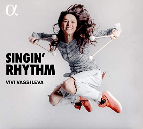 A woman jumps in the air holding mallets, album cover for "Singin' Rhythm" by Vivi Vassileva.