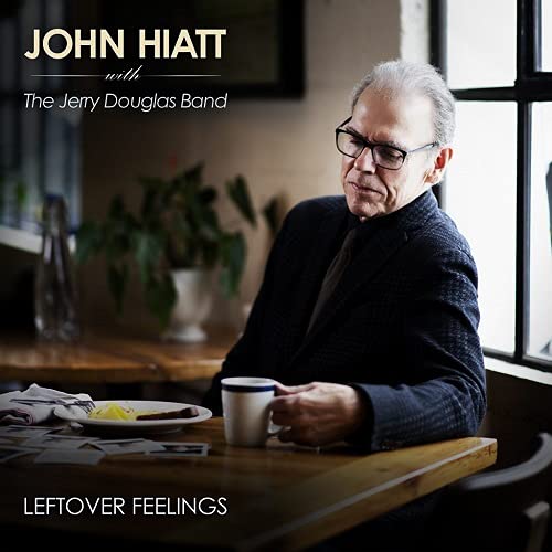 John Hiatt portrait with foliage, coffee, and a newspaper.