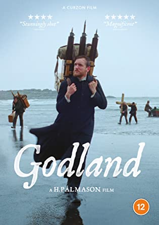 Man carrying a large load on a beach, film "Godland" DVD.