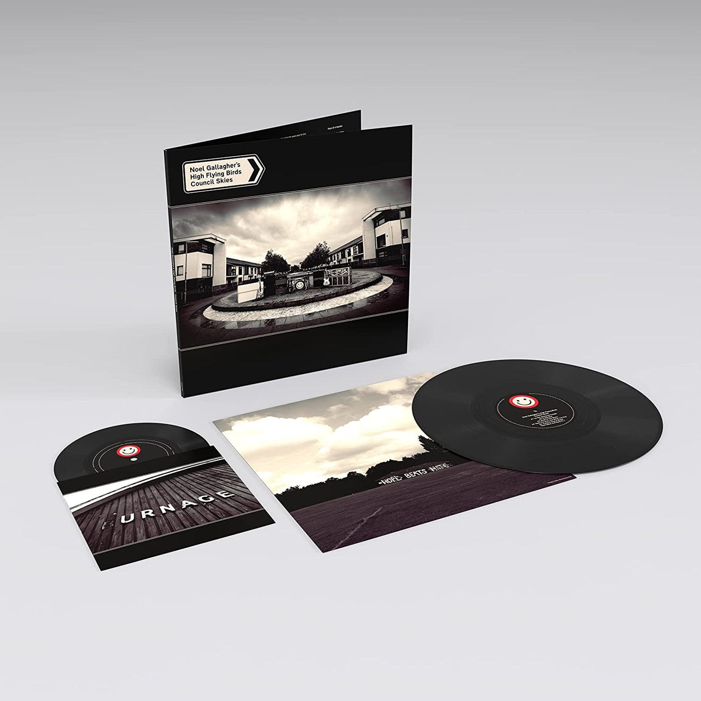 "Vinyl record and album cover with black sleeve and monochrome housing estate image."