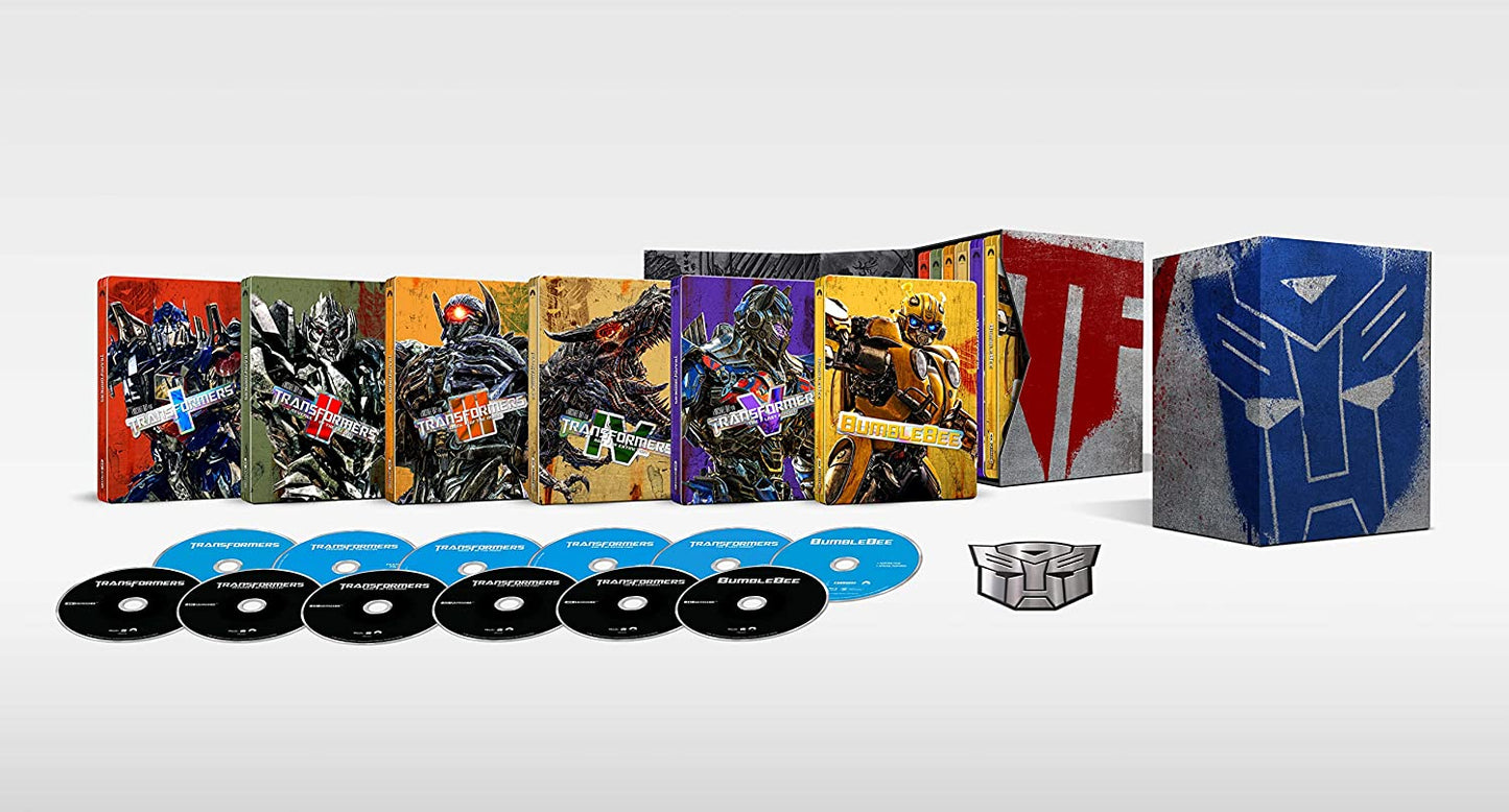 "Seven Transformers movie steelbooks, discs, and Autobot symbol on a white background."