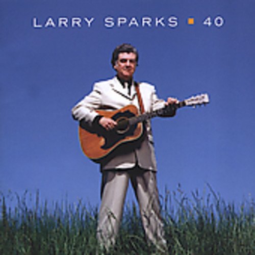 Man in white suit holding guitar stands in tall grass against blue sky on album cover.