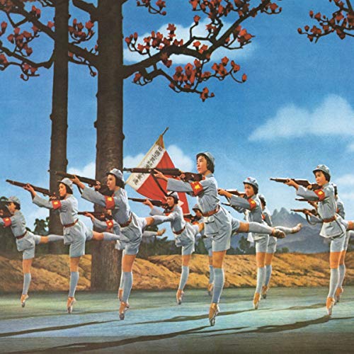Ballet dancers in uniform pose with rifles under a flowering tree.