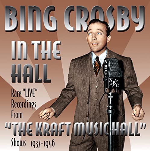 Bing Crosby in a suit speaking into a vintage microphone.