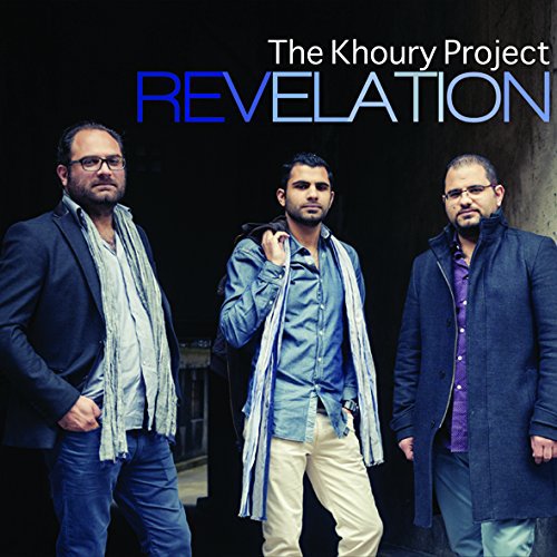 Three men stand in front of a dark background, wearing coats and casual attire.