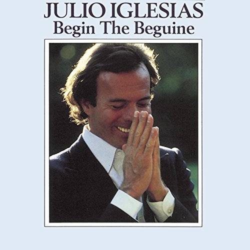 "Album cover with Julio Iglesias in a suit, hands clasped, on a grey background."