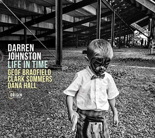 CD cover: boy with painted face, standing in a gravel yard.