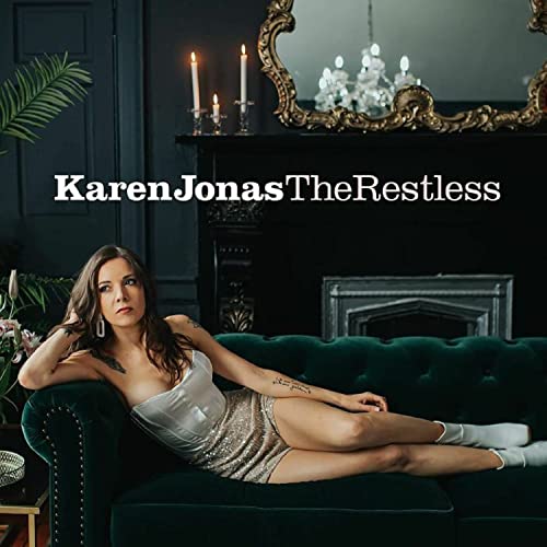 A woman in a white top reclines on a dark green velvet sofa.