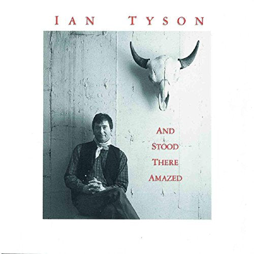 "Album cover with man sitting against wall, cow skull above, and red text on white background."