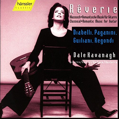 "Dale Kavanagh sits with a guitar, eyes closed, on a simple wooden chair."