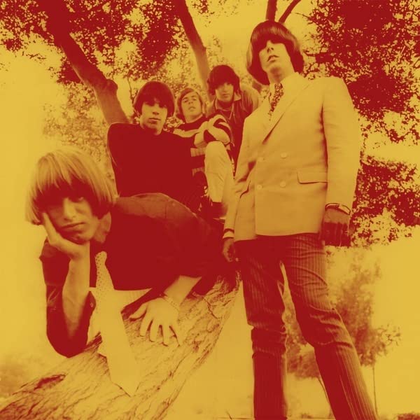 Sepia-toned photo of a four-person band posing outdoors beneath trees.