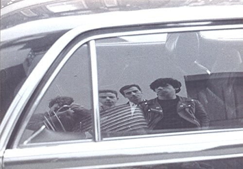 Black and white photo of four people seen through a car window.