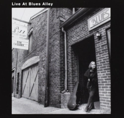 Black and white album cover featuring a woman standing in a doorway with a guitar case.