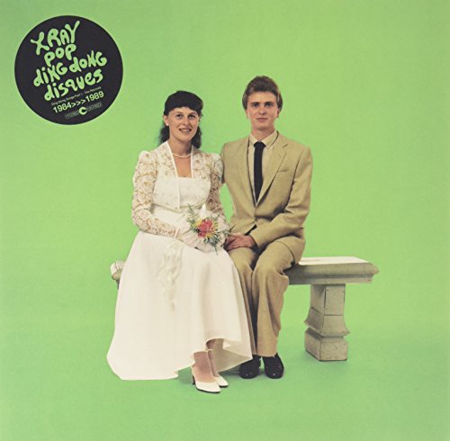 A bride and groom sit on a bench against a green background, album cover art.
