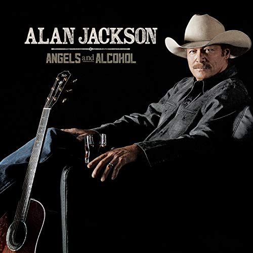 Alan Jackson wearing a cowboy hat, holding a glass, with an acoustic guitar nearby.
