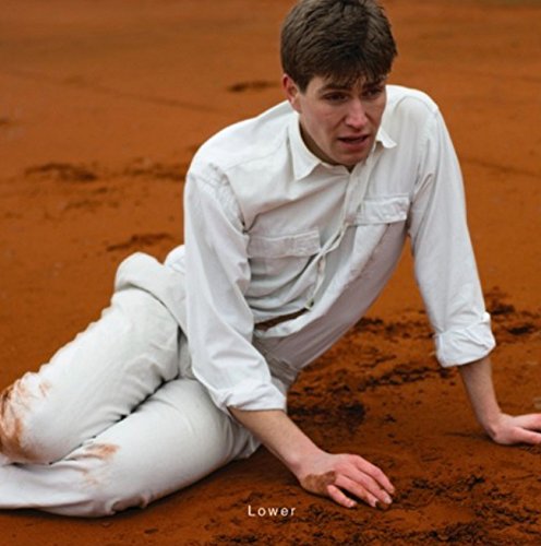 Man in white shirt and pants sitting on red dirt, with "Lower" text below.
