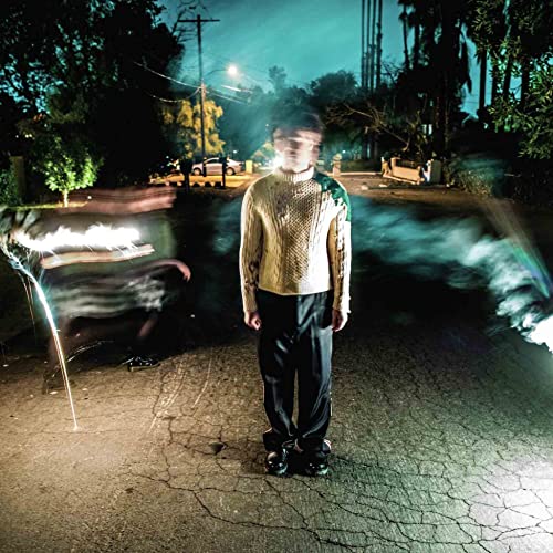 CD cover: man in sweater stands on cracked pavement at night.