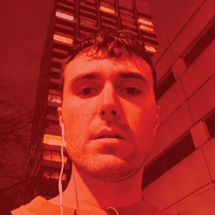 Close-up portrait of a young man with earphones, red lighting.