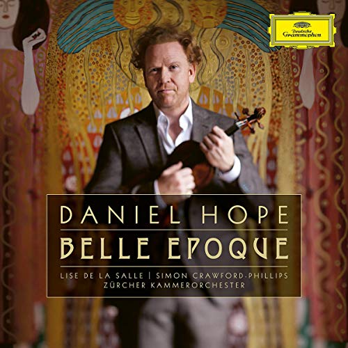 Man in a suit holding a violin, against an ornate background.