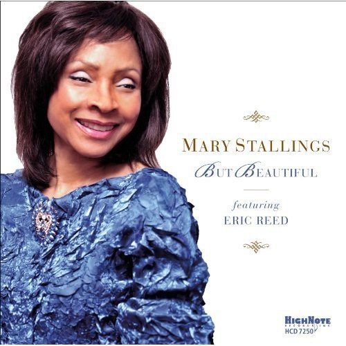 "Album cover with a smiling woman in blue dress and gold text on white background."