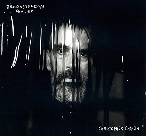 A black-and-white album cover featuring a man's face behind broken glass.