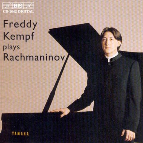 CD cover featuring a man standing beside a grand piano, wearing a black suit.