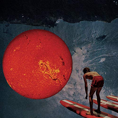 Surfer silhouetted against a large red sun and blue ocean waves.