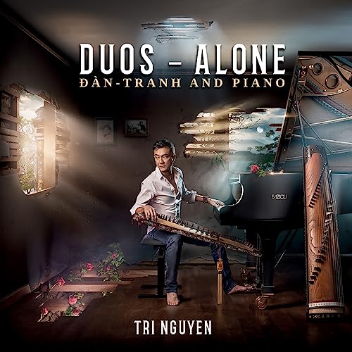 Man playing a Vietnamese zither with a piano in a rustic room.
