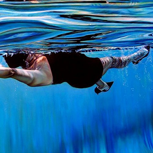 Person swimming underwater, viewed from below with distorted water surface.