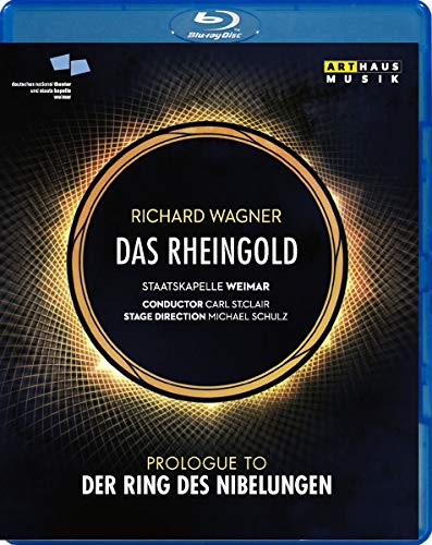 The image depicts a Blu-ray disc case for "Das Rheingold". * The case is blue with a black cover featuring a gold circle. * The title and composer's name are displayed prominently in white text. * Additional details about the production are listed below the title. * The background of the cover has a grid pattern with a gold glow. Alt text: "Blue Blu-ray case with black cover featuring gold circle and white text."