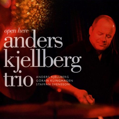"Album cover with a man playing drums, lit with red light, and white text."