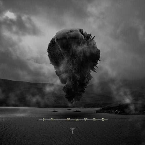The image depicts a haunting scene with a dark, ominous creature emerging from the water, surrounded by turbulent waves and a stormy sky. The creature's body is shrouded in darkness, making it difficult to discern its features. The title "In Waves" is prominently displayed at the bottom of the image, accompanied by a logo that appears to be a stylized letter "T". The overall atmosphere is foreboding and intense, suggesting a dramatic and powerful musical experience. A suitable alt